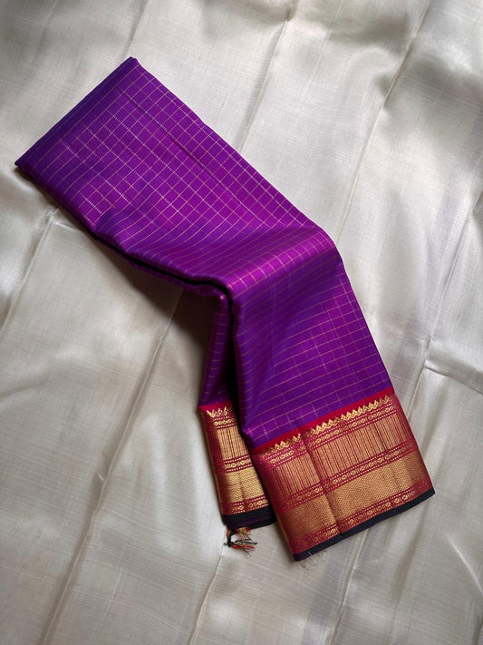 Amethyst Zari Kattam – Pure Kanchipuram Silk Saree
Rich Amethyst Purple Body with Golden Zari Checks
Broad Gold Zari Border with Red Highlights & Temple Motifs
Radiant Ruby Red-Orange Pallu with Lustrous Zari Stripes

Silk Mark Certified, delivery in 2 we