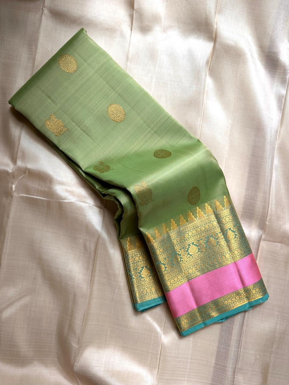 Rose pistachio meadow  – Pure Silk Kanchipuram Saree
Pista Green Body with Coin Paving Mayil Zari Buttas 🦚
Borders in Aqua & Rose with Pillayar Moggu Motifs ✨
Grand Aqua Pallu in All-Over Zari Brocade Weave
Silk Mark Certified | ships in 2 weeks