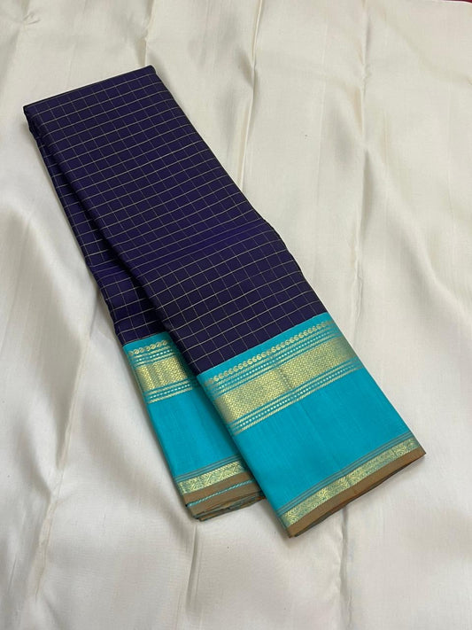 Indigo Teal Kattam – Pure Silk Kanchipuram Saree
Deep Indigo Body with zari Kattam Checks
Teal Contrast Korvai Border with maanga pet and mayil kann border, maanthulir selvedge  , silk mark certified -ships in two weeks
