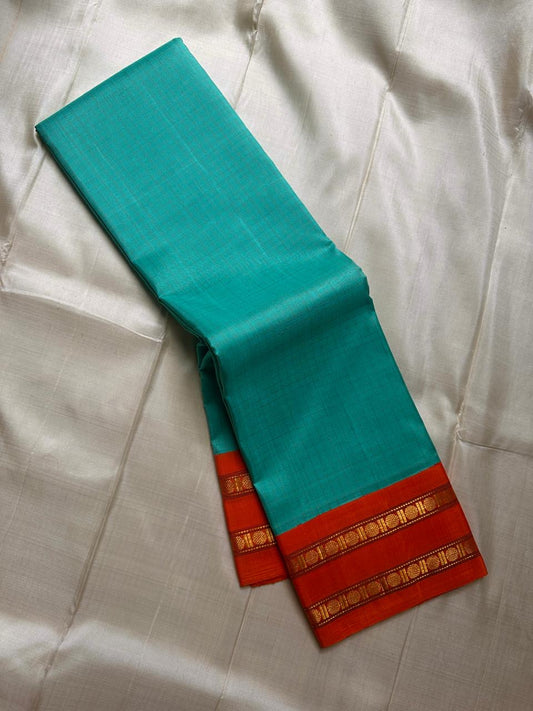 Sharvani blue sea green – sea green  Checked Silk Saree with an Orange red  shot color Zari Border & Vibrant Pallu A timeless silk saree featuring a cream body with delicate red checks, complemented by a striking churan orange  zari border pallu.