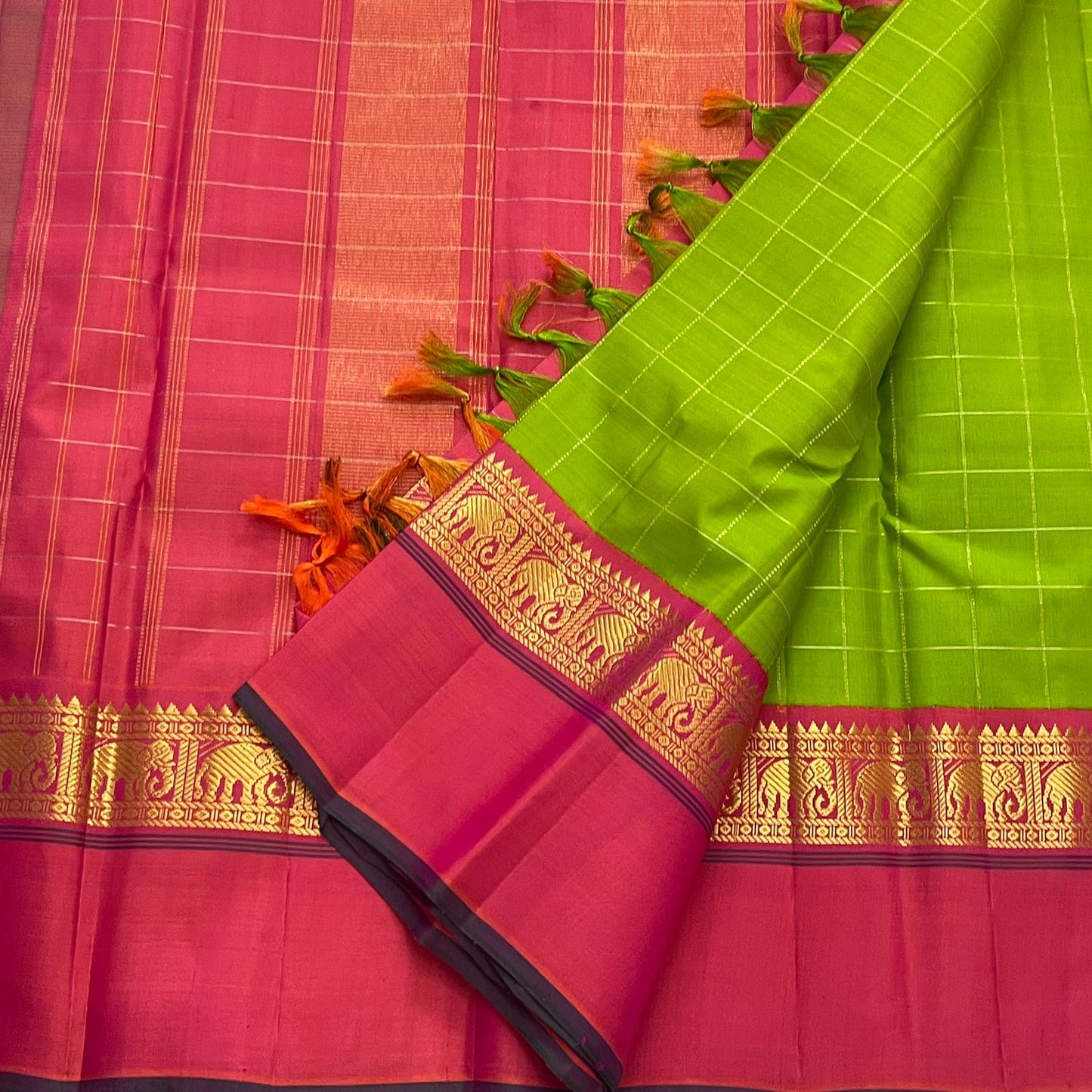 Valli Pachai – Kanchipuram Pure Silk Saree

Parrot-green body in kattam (grid) checks with subtle zari lines

Korvai contrast rani-pink borders featuring gaja (elephant) procession & temple reku motifs

Rich rani-pink zari pallu with vertical bands