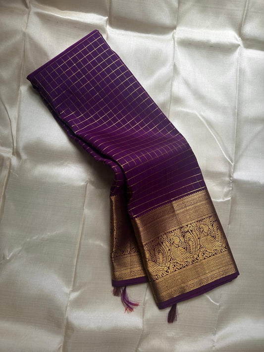 Aubergine Amber Kattam – Pure Kanchipuram Silk Saree
Deep Aubergine Purple Body with Gold Kattam Checks
Grand Zari Borders with Majestic Peacock Motifs
Contrast Amber-Orange Pallu with Rich Zari Detailing
Silk Mark Certified | ships in two weeks