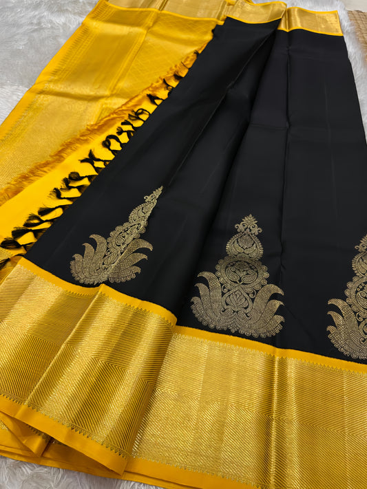 A striking black silk saree adorned with rich gold-yellow zari work, exuding timeless elegance and regal charm.