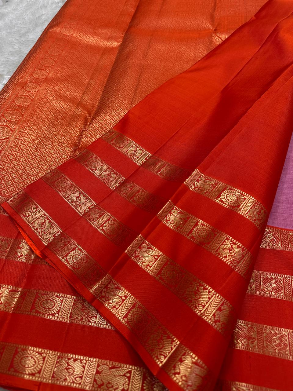 Thamarai Vermillion — Pure Kanchipuram Silk Saree
Soft orchid-pink body with zari lotus buttas and striking vermillion korvai borders, finished with a radiant orange pallu in intricate zari weave.
Silk Mark Certified • Blouse Stitching Available ($30) •