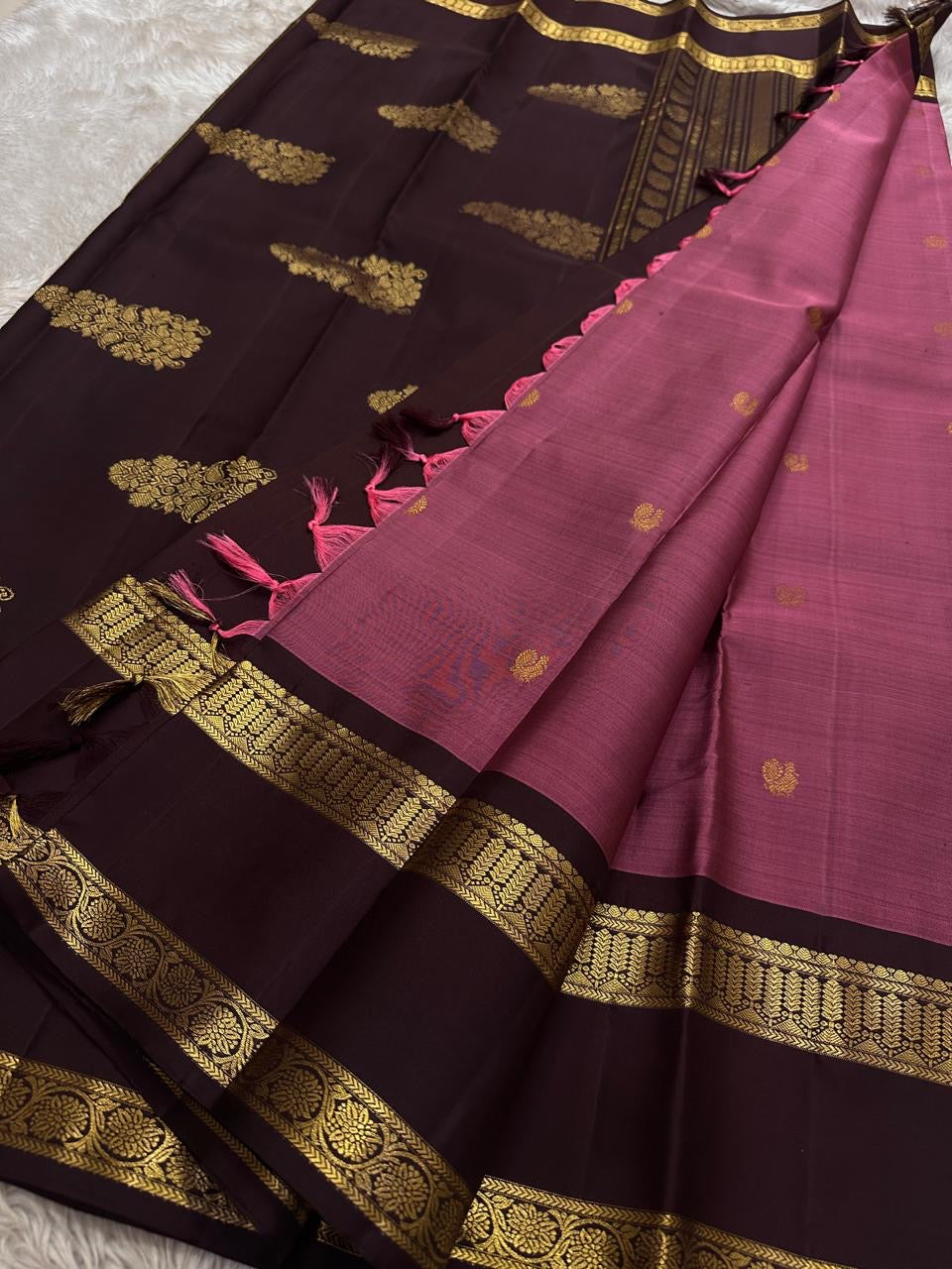 Maroon body with gold buttas and contrast coffee pallu with zari woven border and tassels