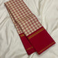 Cream silk saree with red kattam checks draped to show a deep red border finished with narrow gold zari woven stripes.