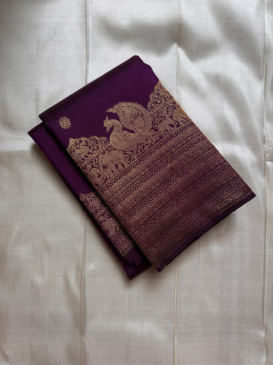 Swarna
Majestic Purple Pure Silk Kanchipuram Saree with Broad Varisaipet Zari Border,Intricately Woven Peacock and Elephant Motifs alongside border . Peacock motifs all over.