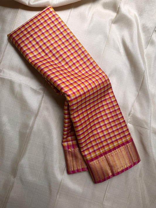 A classic Kanchipuram in Pattani Kattam checks with pink, magenta, mustard, and cream.
Finished with a contrast pink border and pallu.
Paisley and chakram motifs in a graceful grid add timeless charm.
