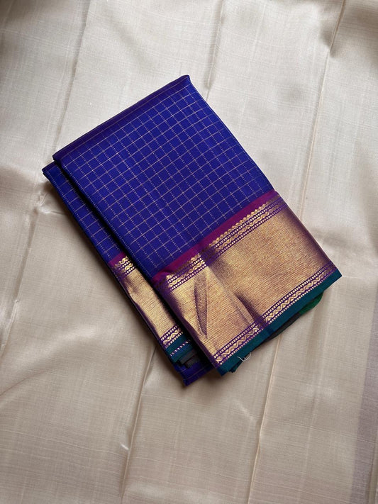 Sapphire Zari Kattam – Pure Kanchipuram Silk Saree
Brilliant Sapphire Blue Body with Gold Zari Checks
Broad Golden Border with Magenta Highlights & Temple Motifs
Royal Magenta Pallu with Lustrous Zari Stripes

Silk Mark Certified, delivery in 2 weeks