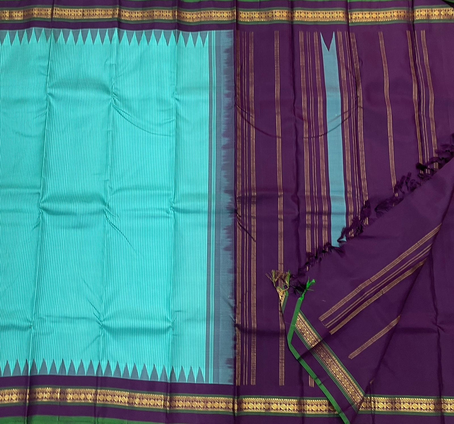 Gopura Neelam — Kanchipuram Pure Silk Saree

 

 

Teal-green body with micro kattam checks for a sleek drape

Regal aubergine korvai border with gopuram/temple motifs & gold zari

Parrot-green selvedge for a fresh, festive pop of contrast

Aubergine pall