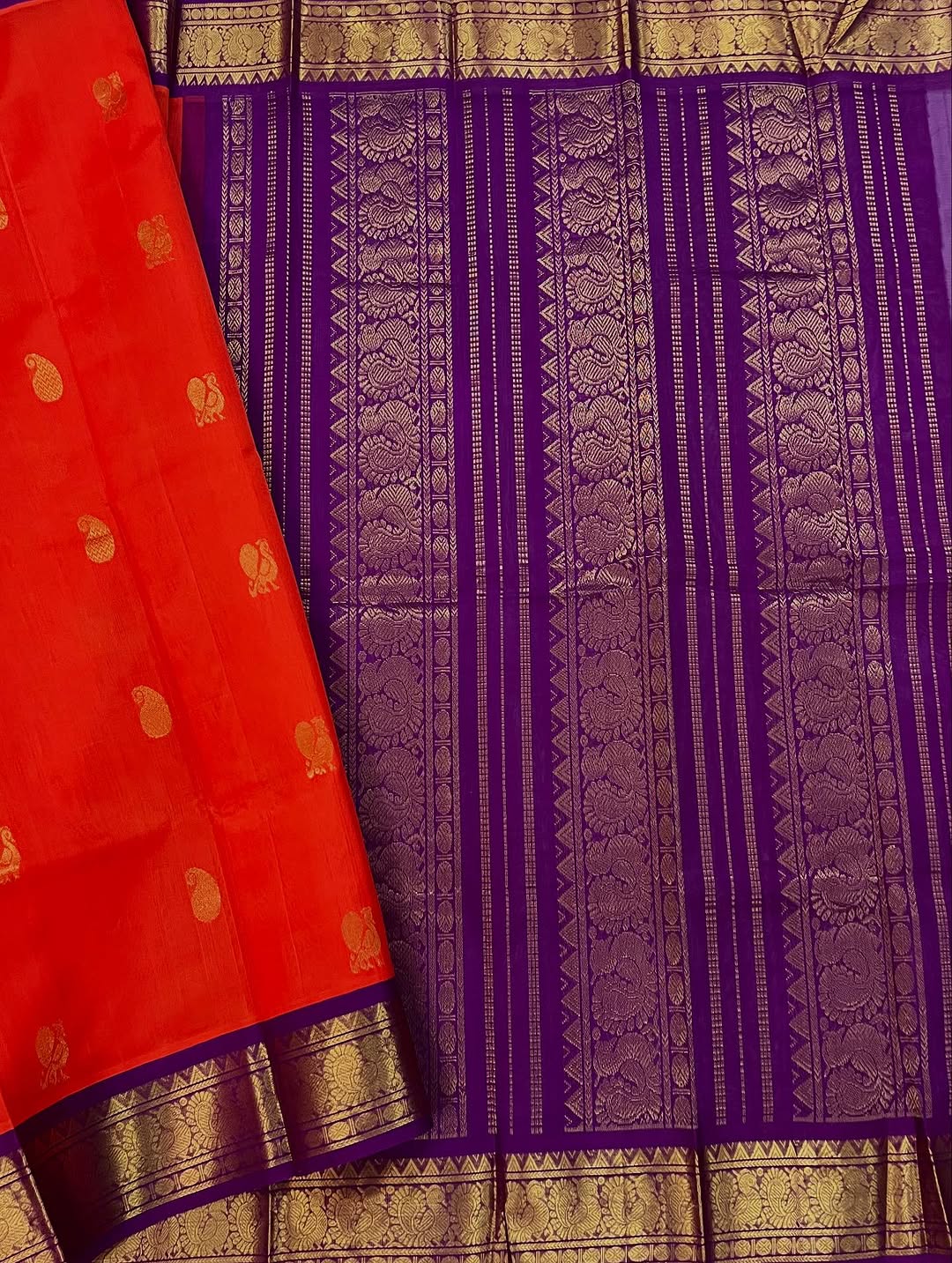 An exquisite blend of tradition and vibrancy, this silk cotton saree features a radiant orange body adorned with elegant gold zari buttas, The rich contrast border and pallu in royal purple and intricately woven with traditional gold zari motif