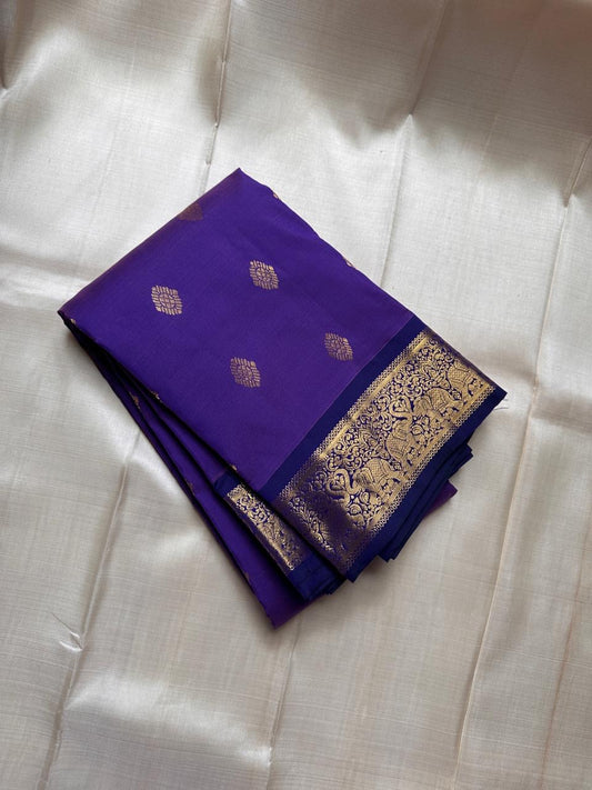 Vadamalli Yaanai – Pure Kanchipuram Silk Saree
Royal purple body with delicate gold zari floral medallion buttas
Ornate yaanai procession borders with vine detailing in zari
Ships in two weeks silk mark certified