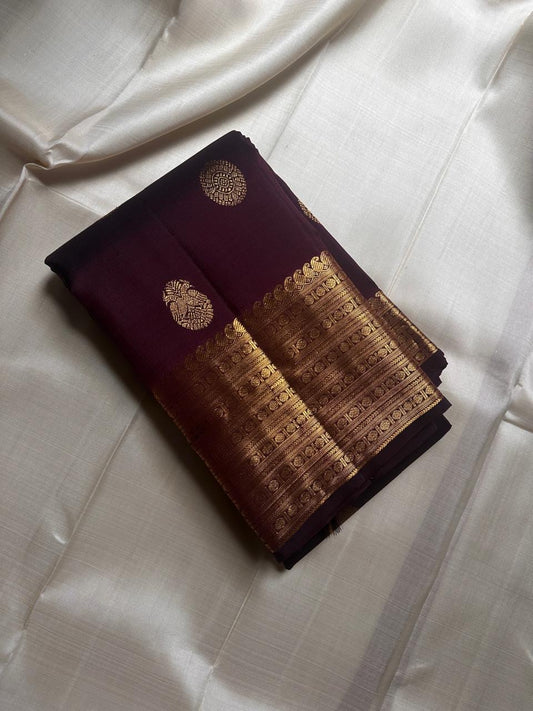 Cholai – Orchard at Dusk ✨ A pure Kanchipuram silk in deep purplish-brown, adorned with regal Gandaberunda 🦅 and delicate Kamalam 🌸 motifs. Its gold zari border layers Varisaipet, mango paisley 🥭, Rudhraksham, and Vanki for a true heritage masterpiece