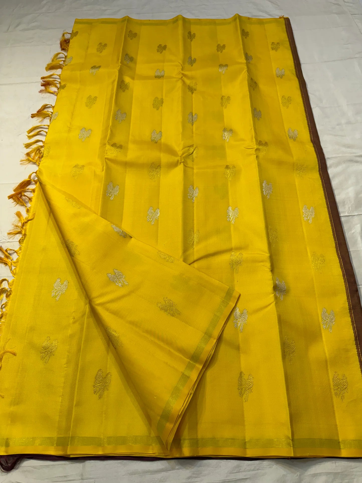Kanaka Mayuri — Pure Silk Kanchipuram Saree
Haldi / Marigold Yellow with Silver-Zari Peacock Buttas ✨
Minimal Self Borders • Contrast Plum Brocade Pallu 💜
Handwoven in Pure Mulberry Silk | Silk Mark Certified ✅
Ships in Two Weeks Free | Idam Living