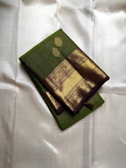 Forest Gold – Pure Kanchipuram Silk Saree
Leaf-green body with fine pin stripes.
Zari leaf buttas for subtle sparkle.
Coffee-maroon korvai border in antique gold.

Silk Mark Certified, delivery in 2 weeks