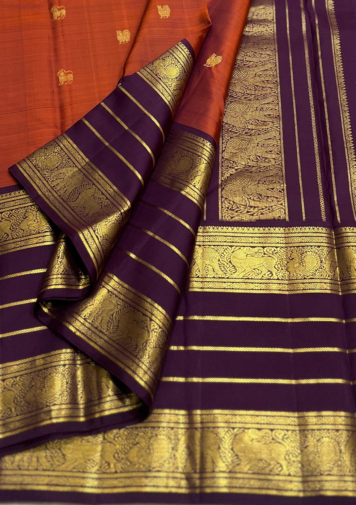 Karpagam – Burnt Orange & Coffee Elegance ✨🪔
A glowing burnt orange body adorned with gold zari peacocks 🦚 and mythical Yazhi 🐉 motifs. The deep coffee border shimmers with Varisaipet geometric zari, while the grand pallu unfolds in panels of Vanasring