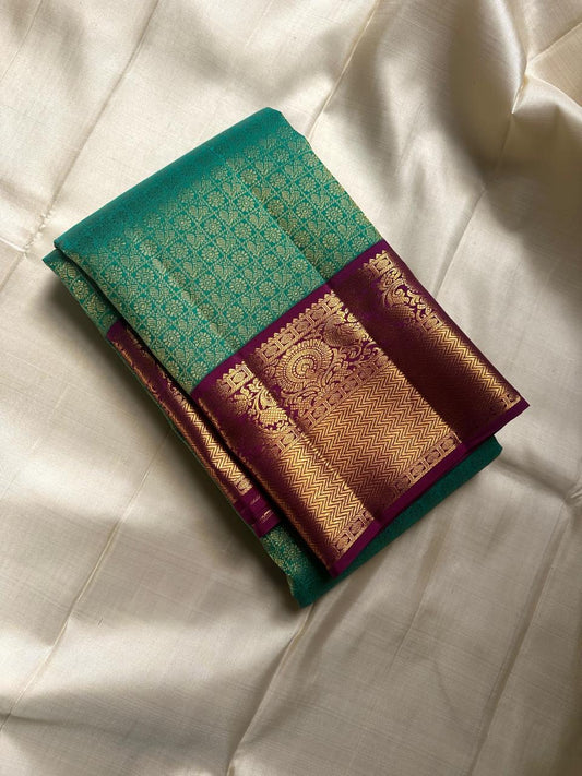 Sindhu- Teal & Purple Kanchipuram Pure Silk Saree with Floral Jaal & Mayil Border
A rich teal base adorned with delicate floral jaal and regal purple mayil borders creates timeless elegance. The diamond-motif pallu adds a bold, sophisticated finish to th