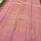 Nirai – A Madras-Inspired Kanchipuram Silk in Amber & Pastel Pink.
Woven with fine podi kattam checks in black, amber orange, and grey.
The pastel pink border with pillayar moggu detailing adds softness, with a  seer zari pallu