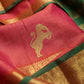 A close-up of a pink silk saree with a gold zari lion motif and green border stripes.