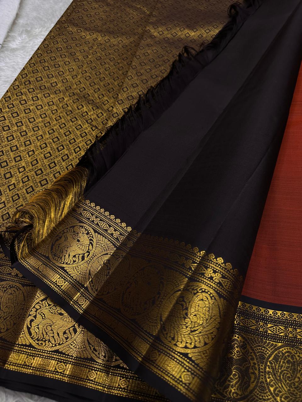 Rust Simha – Pure Silk Kanchipuram Saree
Rust Orange Body with Petite Gold Floral Buttas
Black Korvai Contrast Border with Simha & Annapakshi
Grand Zari Pallu
Comes with Contrast Black Blouse Piece with Zari Border silk Mark certified, ships in 2 weeks