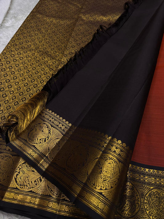 Rust Simha – Pure Silk Kanchipuram Saree
Rust Orange Body with Petite Gold Floral Buttas
Black Korvai Contrast Border with Simha & Annapakshi
Grand Zari Pallu
Comes with Contrast Black Blouse Piece with Zari Border silk Mark certified, ships in 2 weeks