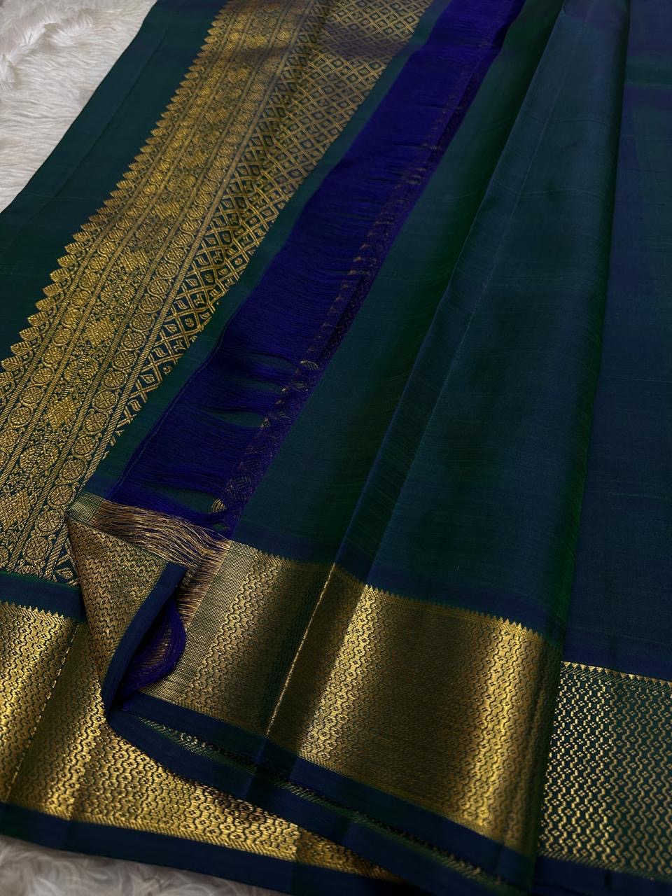 Close view of zari woven border detailing in antique gold with teal silk body and contrast blue pallu edge