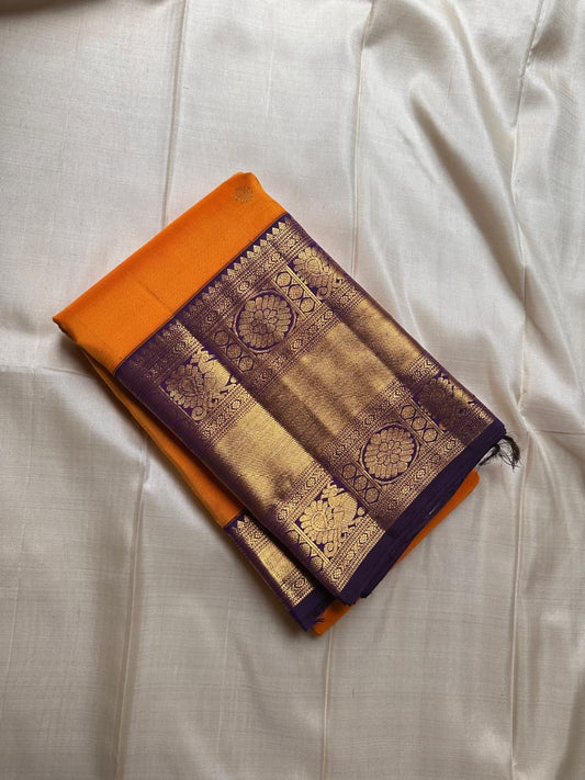 This Maambazha yellow Kanchipuram silk saree features zari mayil buttas and a deep blue rettapet border with kamalam motifs — a timeless blend of tradition and grace.