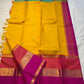 Varna Jaalam — Kanchipuram Pure Silk

Manjal yellow body with gold chakram buttas

Rani pink korvai border with floral & coin zari panels

Magenta–orange chevron pallu with blue–green color block top

Silk Mark Certified • Free Shipping within USA •