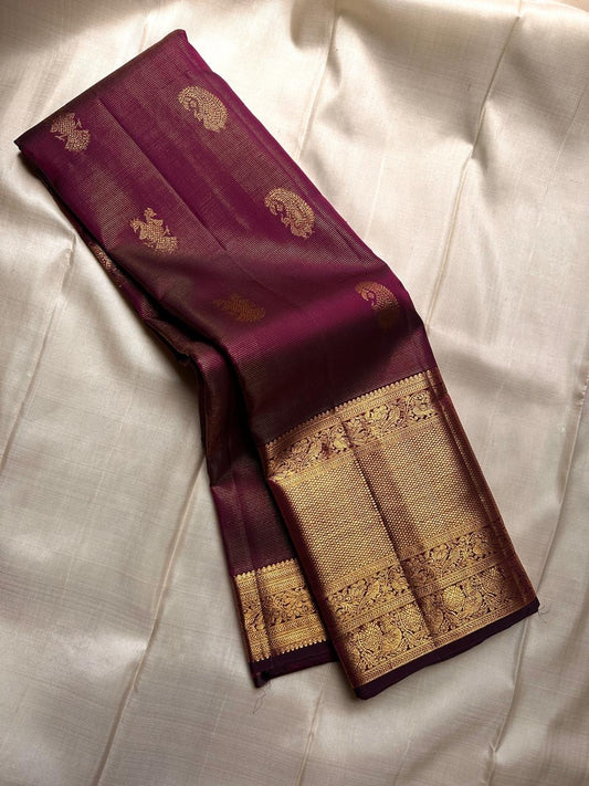 Varnika – Handwoven Kanchipuram Silk Saree in Plum Wine
A regal plum Kanchipuram silk saree adorned with gold zari paisleys and Gandaberunda motifs