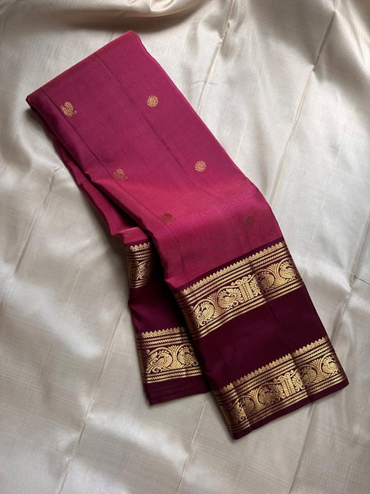 Saanvi – Lotus Pink & Magenta Shot Kanchipuram Silk Saree
Saanvi features zari buttas of mayils and chakrams across the body. A deep wine rettapettu border showcases twin peacocks in a temple arch. The pallu mirrors this grandeur with sorgavasal motifs !