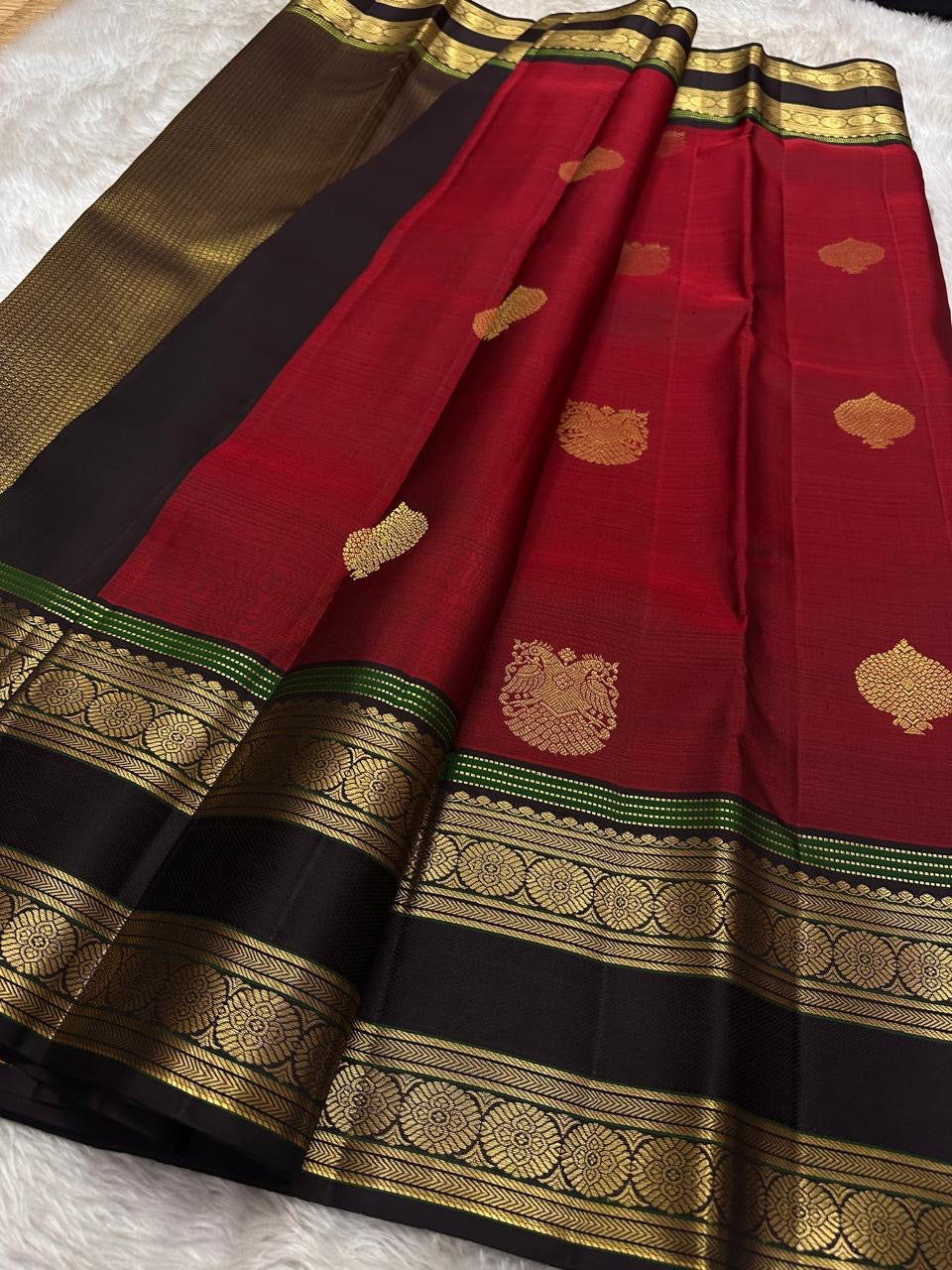 Ishwaryam ❤️🕊️✨

Ruby  Red Handwoven Kanchipuram Silk Saree with Majestic Gandaberunda Zari Adai Motif 🕊️🌟

Ornate Rettapet Border with Delicate Kamalam Seer Floral Detailing 🌺🪡

Deep Coffee Brown Pallu Adding Warmth and Elegant Contrast ☕🌿