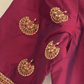 Maroon fabric with gold and red embroidery on a beige background, featuring the IDAM label.