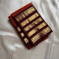 Ember Yazhi – Pure Kanchipuram Silk Saree
Burnt Orange Body with Vaira Oosi Stripes & Yazhi Buttas
Contrast Maroon Varisaipet Border with Gold Zari Panels
Grand Maroon Brocade Pallu with Intricate Motifs

Silk Mark Certified, delivery in 2 weeks
