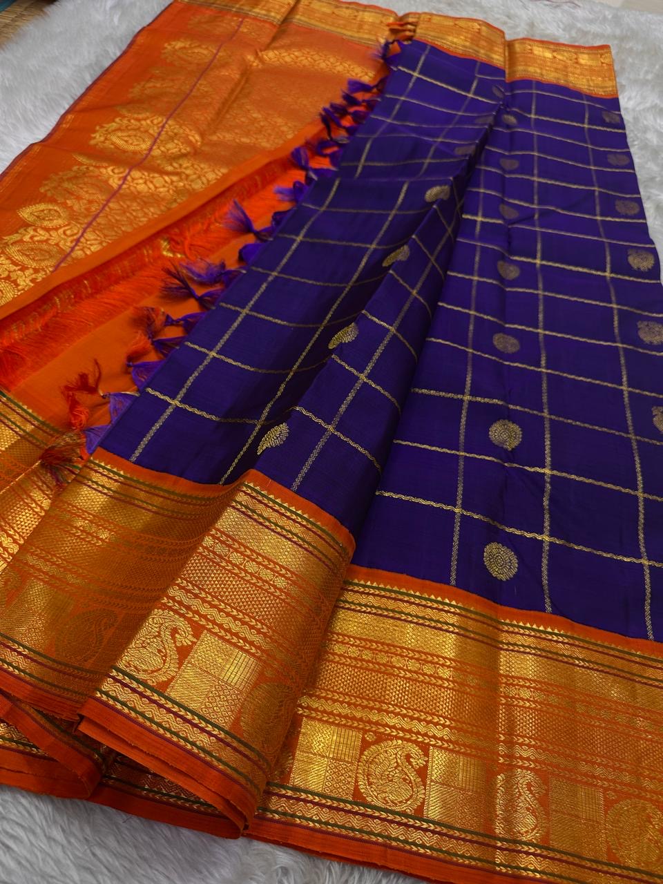 Raga Priya ✨ – Pure Kanchipuram Silk Saree
Royal Purple Body with Zari Kattam & Mayil Chakram Buttas
Sunset Orange Korvai Border in Neli Vanki Zari Pattern
Grand Orange Brocade Pallu with Intricate Weaves
Silk Mark Certified | Fall & Pico Done |