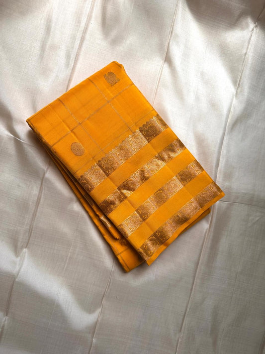 Kanaka – Sunlit Mustard Kanchipuram Silk Saree with Checked Zari Buttas and Gold Striped Border
A radiant weave that captures the warmth of tradition and the glow of celebration