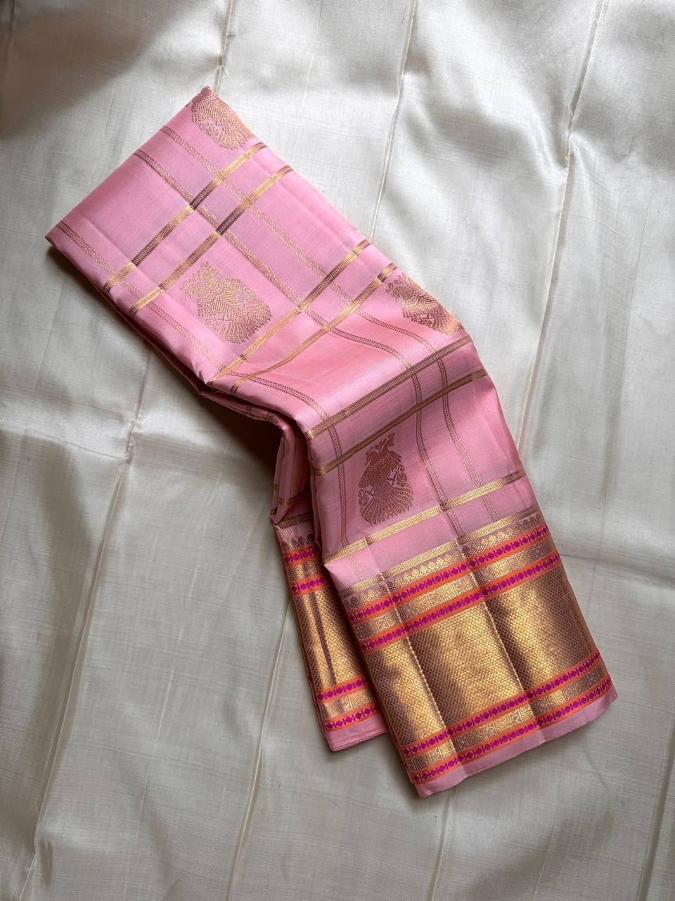 Blush pink Kanchipuram silk saree draped in a pleated stack showing gold zari checks and peacock buttas – Idam Living