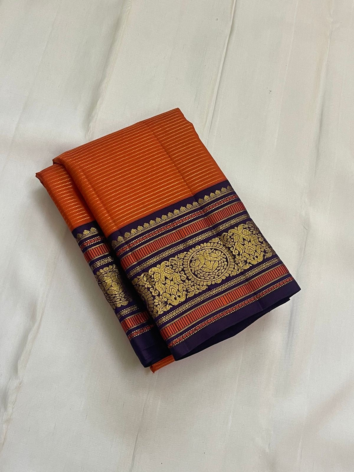 Kesari Annapakshi Chakram
Pure Kanchipuram Silk Saree – Vibrant Kesari Orange Body with Gold Zari Chakram Buttas
Deep Purple Korvai Borders with Majestic Annapakshi & Floral Motifs
Grand Purple Zari Pallu. Silk mark certified , ships in 2 weeks