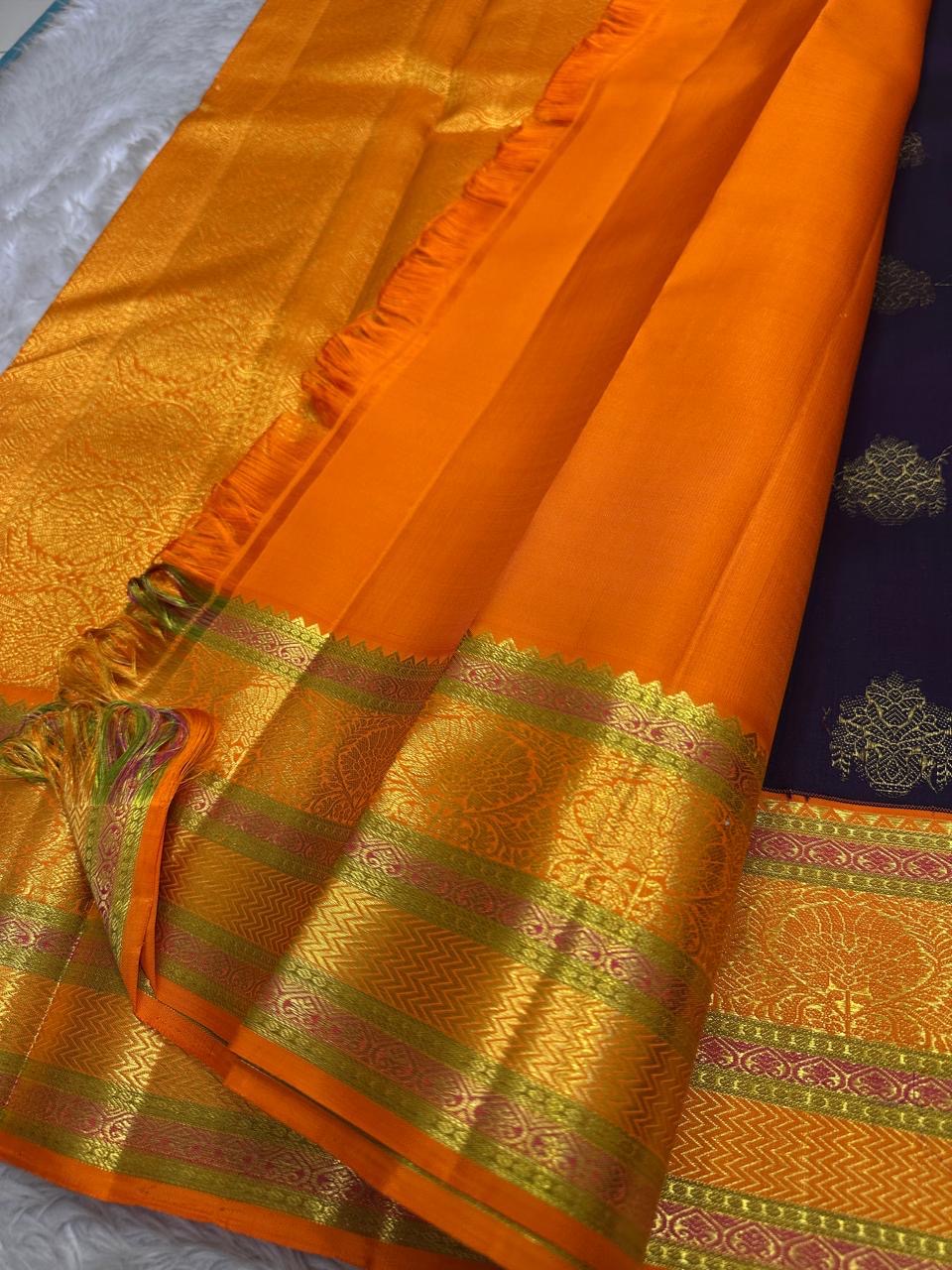 Jamun Purple Kesar – Korvai Kanchipuram Pure Silk Saree

Regal jamun-purple body adorned with antique-gold floral buttas

Kesari-orange korvai border with chakra roundels, vines & chevron zari

Free shipping withinUSA silk mark certified ships in 2 weeks