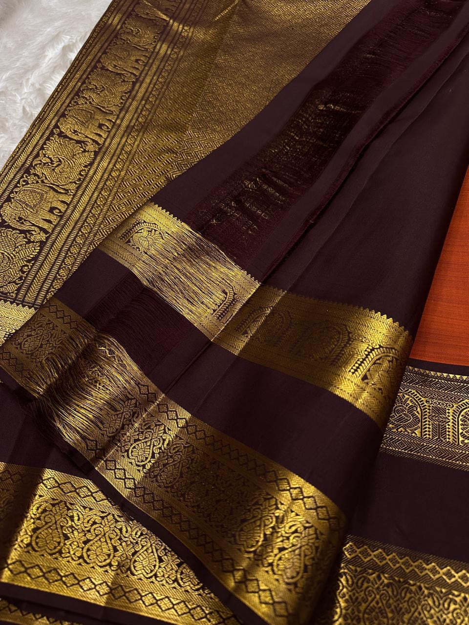 Rust Orange Choodamani — Pure Silk Kanchipuram
Rust-orange body with golden paisley buttas ✨
Deep maroon korvai borders with temple-arch zari 🌸
Grand maroon brocade pallu with elephants & florals 🪔
Silk Mark Certified • Free Shipping USA • Ships in Two