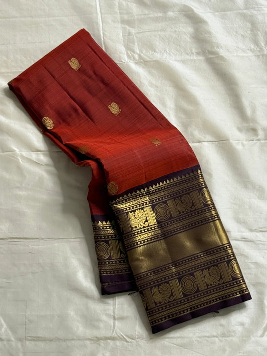 Aruna Mayil – Pure Korvai Kanchipuram Silk Saree

Brick red body with zari rosette buttas

Grand coffee-brown korvai border & pallu with peacock panels, medallions & temple teeth in rich gold zari

Silk Mark Certified | Blouse Piece Included | Fall & Pico