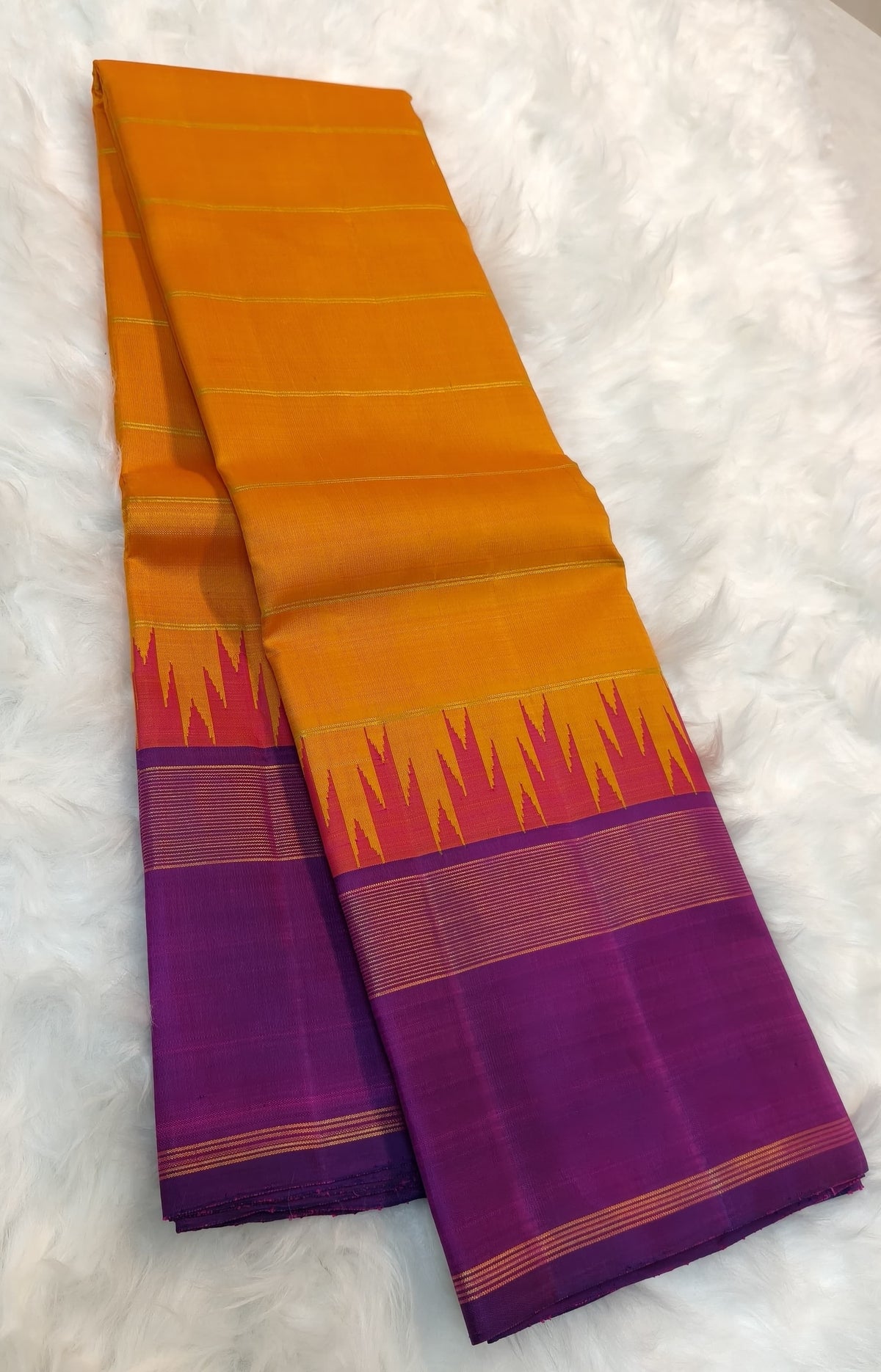 Open view of the orange silk body and contrasting purple Korvai border joined by pointed pink reku detailing.