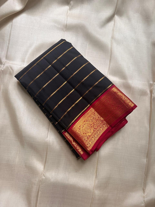 Black with Gold zari stripes , thandavalam stripes run across the body like rays of light. Framed with a bold red border