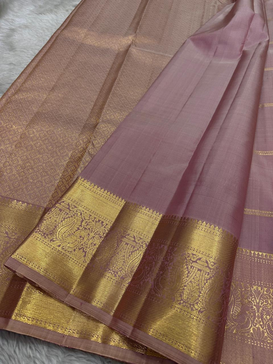Lilac Mayil – Pure Kanchipuram Silk Saree
Ash-Lilac Body with Zari Kattam Checks & Buttas
Broad Antique-Gold Peacock Zari Borders
Grand zari Pallu 
Silk Mark Certified | Fall & Pico Done | Blouse Stitching Available | ships in two weeks Free