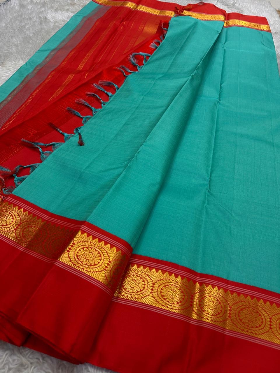 Rama green handloom Kanchipuram silk saree fully spread out, featuring rich red kaal erangina pallu and traditional gold zari motifs.
