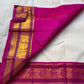 Close-up of fuchsia pallu with gold zari woven motifs and border, partially folded over the ivory saree body.