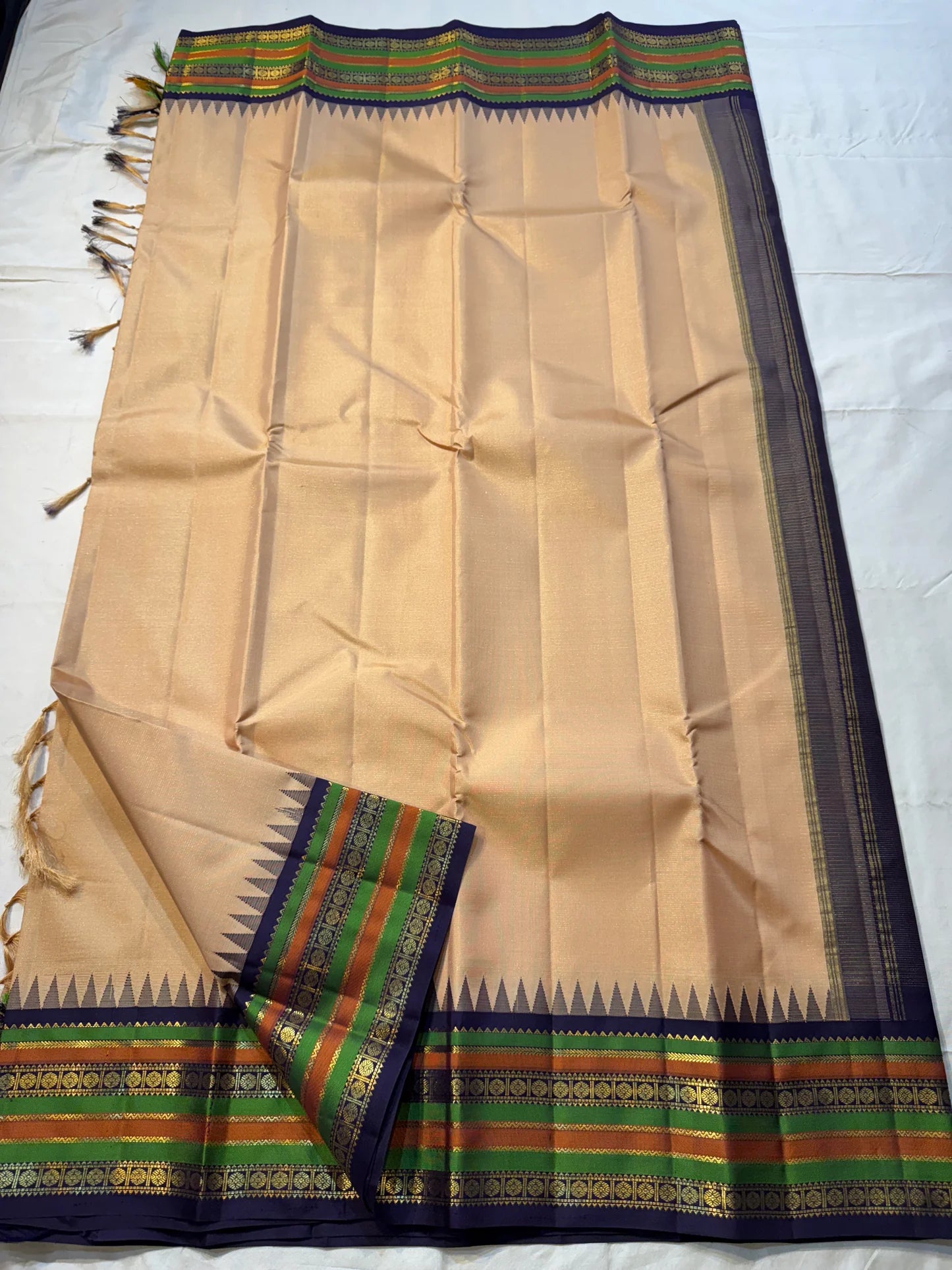 Sandal Temple – Pure Silk Kanchipuram Saree
Sandal Body with mild sheen , pillayar moggu   ✨
Indigo-Purple Korvai Border with Green & Ochre Stripes
Temple Gopuram Zari Edging & Grand Brocade Pallu
Silk Mark Certified | ships in two weeks