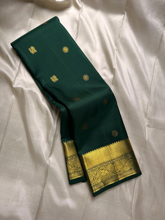 Agnika – Green Kanchipuram Silk Saree with Mayil Chakram Butta
Fiery and regal, Agnika features a rich green silk body with intricate Mayil Chakram (peacock) motifs and a shimmering zari border—an elegant ode to South Indian tradition.