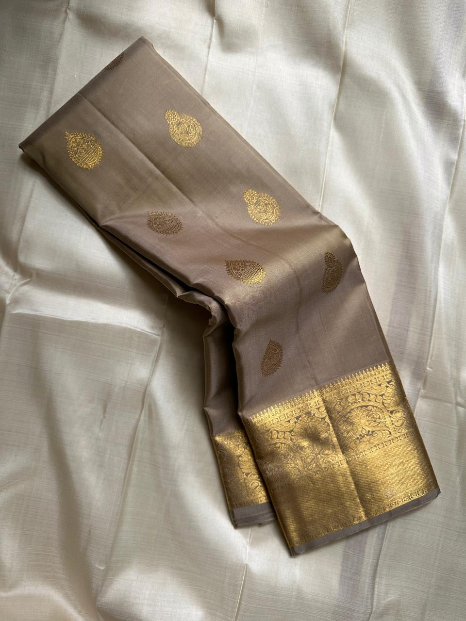 Chiku Orchard – Pure Kanchipuram Silk Saree
Elegant Chiku (Taupe) Body with Gold Paisley Buttas
Rich Antique Gold Zari Borders with Floral Motifs
Grand Gold Zari Pallu with Traditional Kattam Design
Silk Mark Certified | Ready to Ship | ships in two weeks