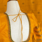Yellow blouse with intricate embroidery on a mannequin against a yellow checkered background