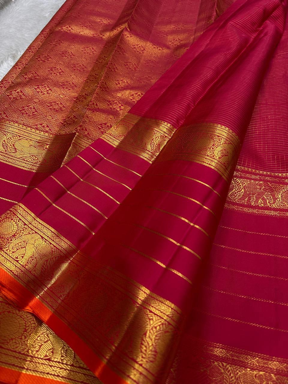 Close-up of pink-red Kanchipuram silk saree pallu featuring dense gold zari weaving and lined body.